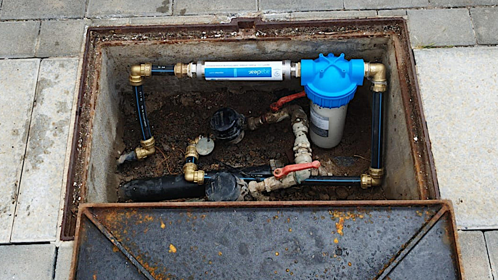 Dispositivo Aqaclear AC820 Hogar instalado en la entrada de agua de un recinto. Se ve el contador de agua y un prefiltro para sedimentos.